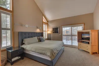 a bedroom with a bed and a dresser and windows at Bitter Brush by Tahoe Getaways -4 BR Pet Friendly, Northstar Home with Hot Tub, Pool Table, & Ski Shuttle in Truckee