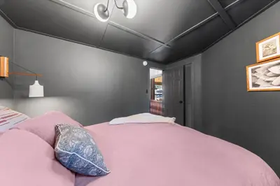 a bedroom with a pink bed and a black wall at Birchwood Retreat by Tahoe Getaways - Newly Remodeled Pet Friendly Home in Alpine Meadows with Wood Fireplace, Hot Tub & Ski Shuttle! in Alpine Meadows