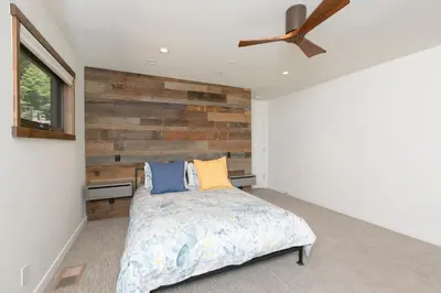 a bedroom with a bed and a wooden wall at Beaver Lake View by Tahoe Getaways - Pet Friendly 3 BR with Hot Tub, Wood Fireplace & Close to Skiing in Kings Beach