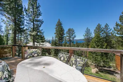 a table on a deck with a view of trees at Beaver Lake View by Tahoe Getaways - Pet Friendly 3 BR with Hot Tub, Wood Fireplace & Close to Skiing in Kings Beach