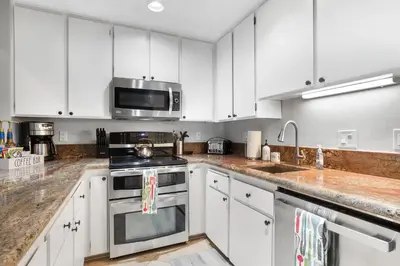 a kitchen with white cabinets and a stove and a microwave at Alpine Escape: Tahoe Oasis Steps from Lake in Carnelian Bay