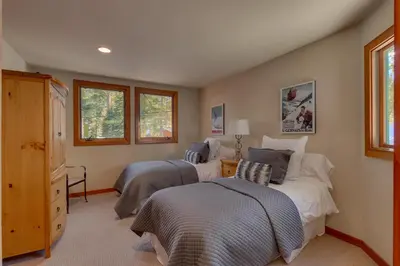 a bedroom with two beds and a dresser and windows at Big John at Alpine Meadows by Tahoe Getaways - Mountain Views, Cozy Fireplace, Shuttle to Slopes! in Alpine Meadows