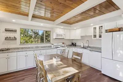 a kitchen with white cabinets and a wooden table at Cedar Chalet by Tahoe Getaways - Stunning 3BR with Fireplace & Pet Friendly in Tahoe Vista