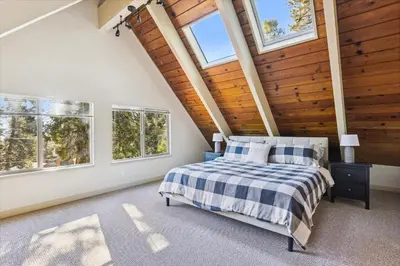 a bedroom with a bed in a room with windows at Cedar Chalet by Tahoe Getaways - Stunning 3BR with Fireplace & Pet Friendly in Tahoe Vista