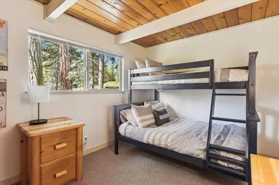 a bedroom with two bunk beds and a nightstand at Cedar Chalet by Tahoe Getaways - Stunning 3BR with Fireplace & Pet Friendly in Tahoe Vista