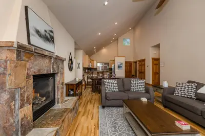 a living room with a large stone fireplace at Cedar Crest at Winter Creek by Tahoe Getaways - 3BR, Walk to Ice Skating, Near Downtown and Northstar with Private Hot Tub! in Truckee