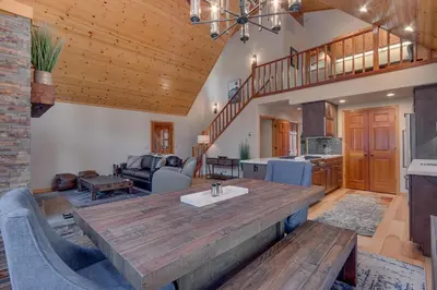 a kitchen and living room with a large wooden table at Cottonwood by Tahoe Getaways - 3BR Tahoe Donner with 2 Bonus Rooms, Hot Tub, Fireplace, Ping Pong & HOA Amenities in Truckee