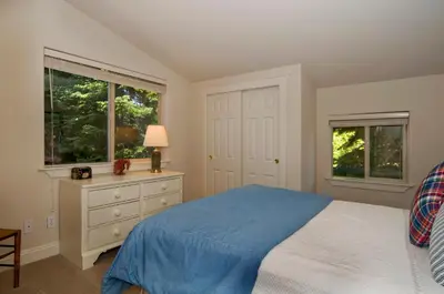 a bedroom with a bed and a dresser and two windows at Big Springs by Tahoe Getaways - 6BR w Ski Shuttle, Fireplace & Entertainment Room in Truckee