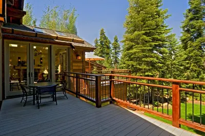 a deck with a table and chairs on a house at Big Springs by Tahoe Getaways - 6BR w Ski Shuttle, Fireplace & Entertainment Room in Truckee