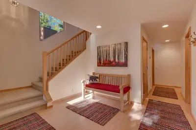 a living room with a bench and a staircase at Deer Hollow by Tahoe Getaways at Northstar - 4BR w Hot Tub, Ski Shuttle, & HOA Amenities in Truckee