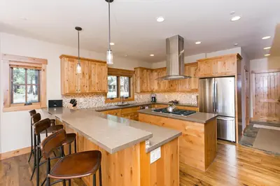 a kitchen with wooden cabinets and a kitchen island with chairs at Caleb's Getaway by Tahoe Getaways at Old Greenwood- 3BR w Bonus Room, Pets Welcome & Ski Shuttle! in Truckee