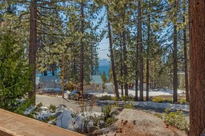 a view of the beach through the trees at Moon Dune Chalet by Tahoe Getaways - Remodeled 3 BR Cabin plus Loft w Fenced Yard & Walk to Beach or Dining in Tahoe Vista