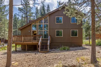a house in the woods with a deck and windows at Rustic Retreat by Tahoe Getaways - 4BR Tahoe Donner Contemporary Cabin w Forest Views, Pet-Friendly & HOA Amenities in Truckee