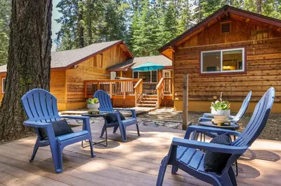 a deck with blue chairs and a cabin at Sunlit Pines by Tahoe Getaways - 2BR in Tahoe Park w Hot Tub, Fenced Yard & Pet Friendly! in Tahoe City