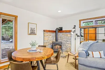 a living room with a table and a fireplace at Sunlit Pines by Tahoe Getaways - 2BR in Tahoe Park w Hot Tub, Fenced Yard & Pet Friendly! in Tahoe City
