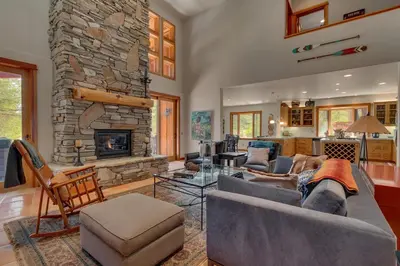 a living room with couches and a stone fireplace at Tranquil Retreat by Tahoe Getaways - 3BR Pet-Friendly Home w Private Hot Tub, Views & HOA Amenities in Truckee