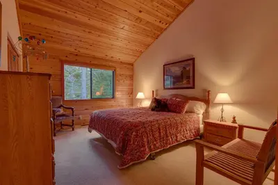 a bedroom with a bed and a chair and a window at Dogwood Place by Tahoe Getaways - 3BR Pet-Friendly Tahoe Donner Home w Hot Tub, Pool Table, Wood Fireplace & HOA Amenities in Truckee