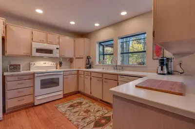 a kitchen with white appliances and wooden cabinets at Dogwood Place by Tahoe Getaways - 3BR Pet-Friendly Tahoe Donner Home w Hot Tub, Pool Table, Wood Fireplace & HOA Amenities in Truckee