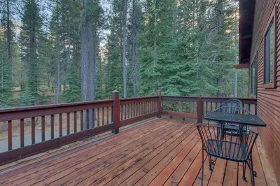 a wooden deck with a table and chairs on it at Dogwood Place by Tahoe Getaways - 3BR Pet-Friendly Tahoe Donner Home w Hot Tub, Pool Table, Wood Fireplace & HOA Amenities in Truckee