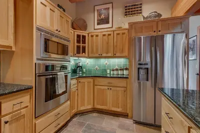 a kitchen with wooden cabinets and a stainless steel refrigerator at Fireside Lodge at Northstar By Tahoe Getaways - 4BR w Hot Tub, HOA & Ski Shuttle in Truckee