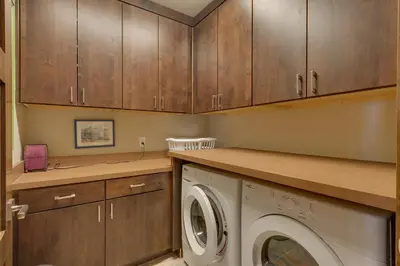 a laundry room with wooden cabinets and a washing machine at Gondola Getaway- Ski-in Ski-out - Luxury 4 BR, Private Hot Tub, HOA Amenities in Truckee