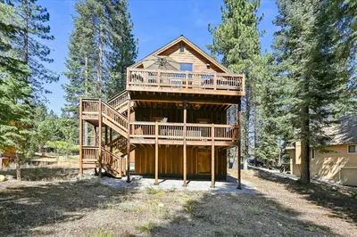 a large log house with a large deck at Graystone Retreat - Modern Retreat w Hot Tub & HOA Amenities in Truckee