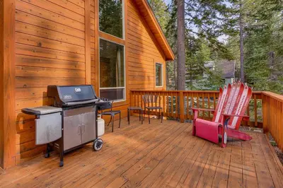 a screened in porch with a bbq and two chairs at High Country Lodge by Tahoe Getaways - Tahoe Donner 4BR w Hot Tub, Air Conditioning, EV, HOA, Shuffleboard and Horse Shoe Pit in Truckee