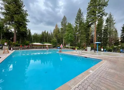 a large blue swimming pool with trees in the background at Indian Hills at Northstar by Tahoe Getaways - Spacious 4 BR, Private Hot Tub, Wood Fireplace, and HOA Amenities in Truckee