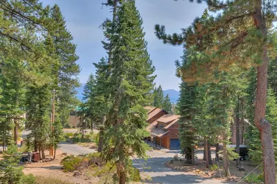 a house in the middle of a forest of trees at Mountain Escape at North Shore - Upscale 4BR Easy Walk to Lake & Private Hot Tub! in Carnelian Bay