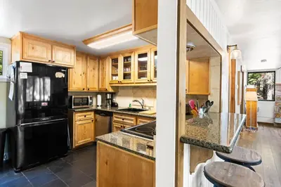a kitchen with wooden cabinets and a black refrigerator at Ellis Peak Retreat - Hot Tub, Wood Fireplace, Close to Tahoe City & Dining in Tahoe City
