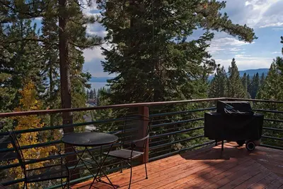 a chair and a table on a deck with trees at Pioneer Lake View- 4BR Easy Walk to Town Private Hot Tub - Sleeps 11 in Tahoe City