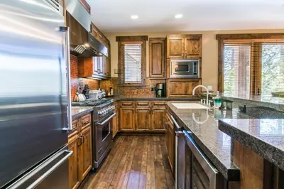 a kitchen with wooden cabinets and stainless steel appliances at Village Walk - Private Hot Tub, HOA Amenities, Pet Friendly, Walk to Lifts! in Truckee