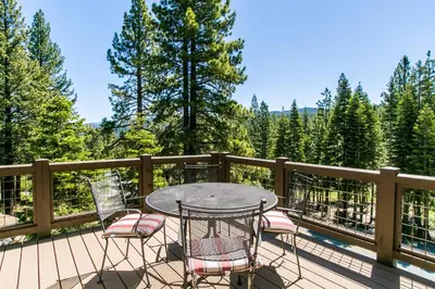 a table and chairs on a deck with trees at Village Walk - Private Hot Tub, HOA Amenities, Pet Friendly, Walk to Lifts! in Truckee
