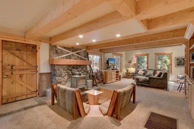 a living room with a stone fireplace and a table and chairs at West Pine Cabin on the West Shore by Tahoe Getaways - 2 BR w 2 Bonus Rooms, Hot Tub, Pool Table & Pet Friendly in Tahoe City