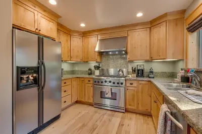 a kitchen with wooden cabinets and a stainless steel refrigerator at Woodcrest at Tahoe Donner 3BR with Pool Table - 3000 sq ft in Truckee