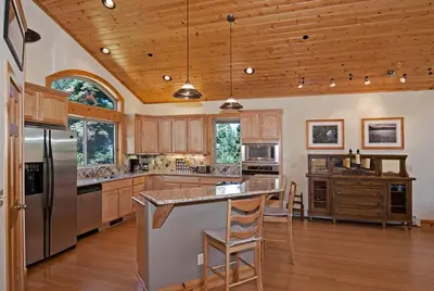 a large kitchen with wooden cabinets and stainless steel appliances at Woodside Lodge on West Shore with Private Hot Tub, Pool Table & Game Room in Tahoma