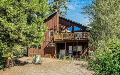 a large wooden house with a deck in the woods at New Listing! Woodland Heights at Tahoe Park- Pet Friendly - Private Beach in Tahoe City