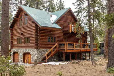 a log cabin in the woods with a large deck at Tahoe Wanderer - 3 BR Luxury Log Cabin with Additional Loft, Private Hot Tub in Tahoe Vista