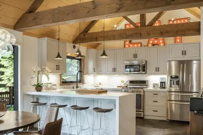 a kitchen with white cabinets and a large island with bar stools at Timber Grove at Tahoe Park - Gorgeous 4BR Cabin - Tahoe Park HOA, Pets OK, Near Skiing in Tahoe City
