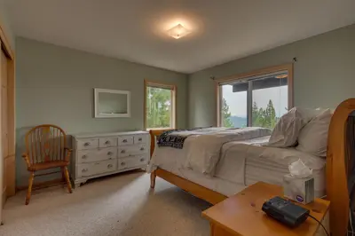 a bedroom with a bed and a chair and a window at Treetop at Tahoe Donner - Pet Friendly 4BR w Gym and Pool Access in Truckee