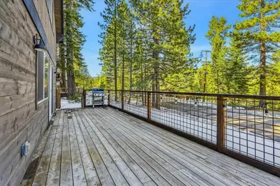 a wooden deck with a fence and trees at Granlibakken Getaway by Tahoe Getaways - West Shore Retreat-Central Location-Hot Tub-Dog Considered-Near Skiing in Tahoe City
