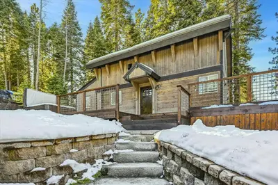 a log cabin with stairs leading to the door in the snow at Granlibakken Getaway by Tahoe Getaways - West Shore Retreat-Central Location-Hot Tub-Dog Considered-Near Skiing in Tahoe City
