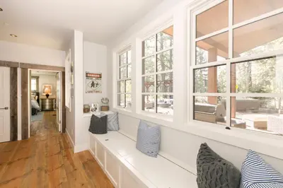 a living room with a long white bench and windows at First Light Farmhouse- Hot Tub- Gourmet Kitchen- Premier Neighborhood in Truckee