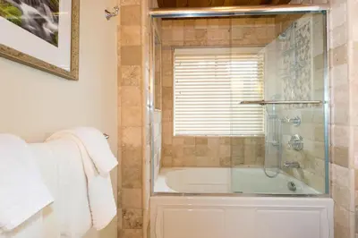 a bathroom with a tub and a shower with a glass door at Victory Place at Palisades - Stunning 5 BR with Private Hot Tub and Pool Table in Olympic Valley
