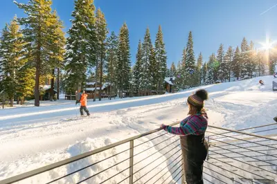two people standing on a fence in the snow at Stellar Ski-in Ski-out Townhouse 8 - Luxury 3 BR w Private Hot Tub and Gym and Pool Access in Truckee