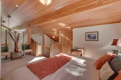 a living room with a bed and wooden ceilings at Creek Side- 4 Primary Suites, Hot Tub, Shuttle to Slopes, Pet Friendly in Olympic Valley