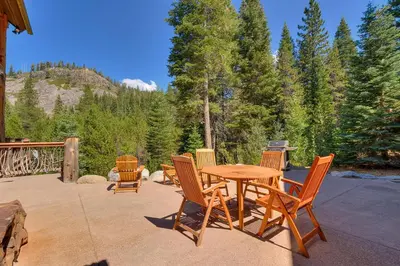 a wooden table and chairs on a patio at Bullshead Lodge- Luxury Estate, 4 Acres on River, Hot Tub, Minutes from the Slopes! in Olympic Valley