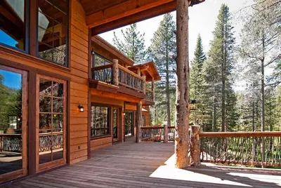 a house with a wooden deck with a balcony at Bullshead Lodge- Luxury Estate, 4 Acres on River, Hot Tub, Minutes from the Slopes! in Olympic Valley