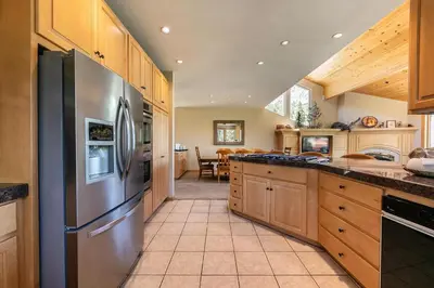a kitchen with a stainless steel refrigerator and wooden cabinets at Eagles Nest by Tahoe Getaways - Pet Friendly with Hot Tub, Pool Table & Shuttle to Slopes in Olympic Valley