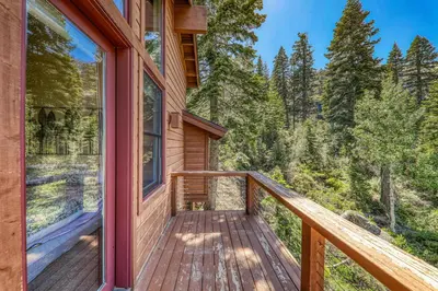 a balcony of a wooden house with a view of the woods at Eagles Nest by Tahoe Getaways - Pet Friendly with Hot Tub, Pool Table & Shuttle to Slopes in Olympic Valley